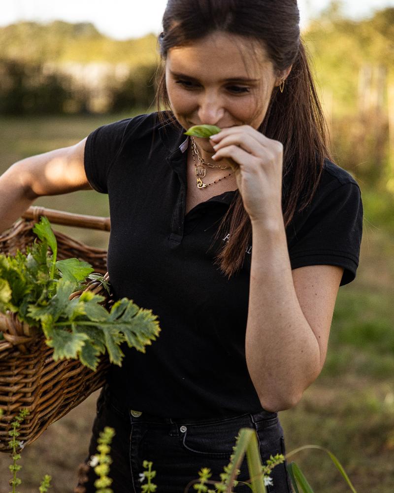 Girl smiling as she smells freshly picked basil leaf