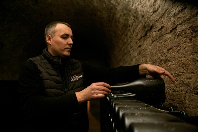 Cellar worked placing champagne bottle on rack in Champagne Lanson cellar