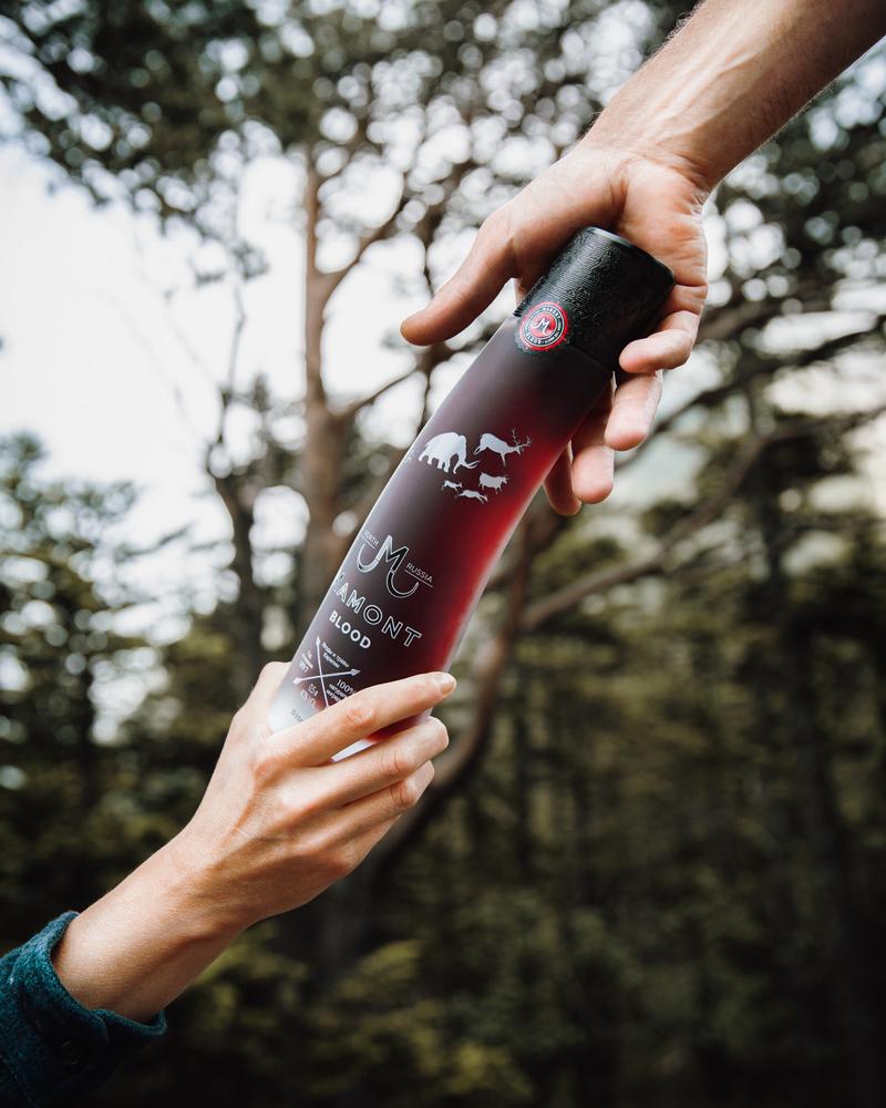 Passing bottle of Mamont Blood vodka between hands in woodland environment