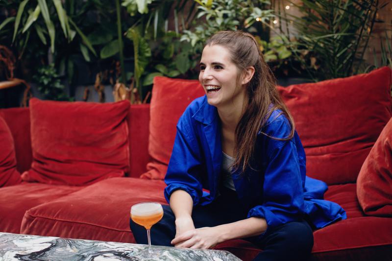 Portrait of Juliette Larrouy sitting on sofa laughing
