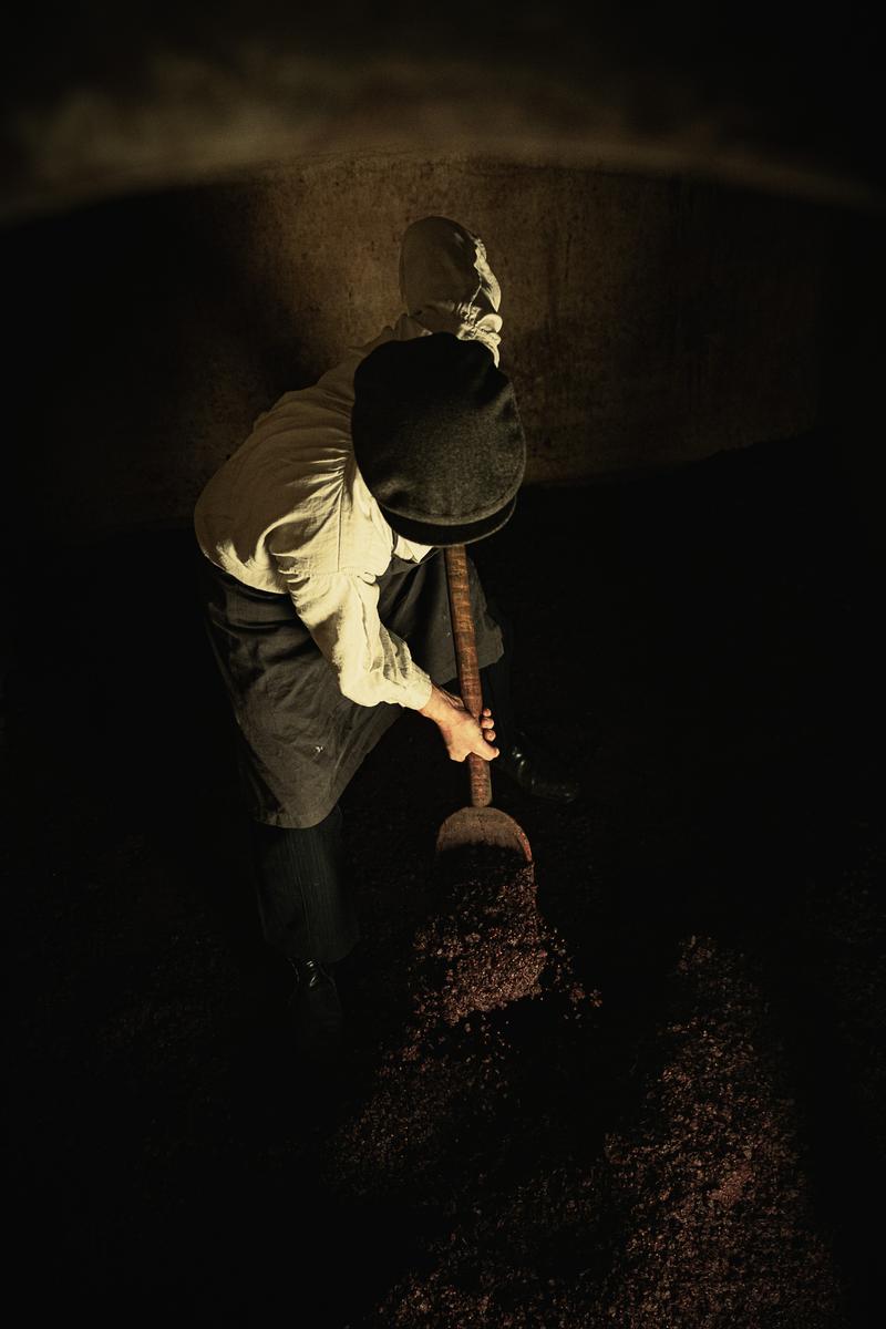 1920s winemaker emptying wine vat with spade