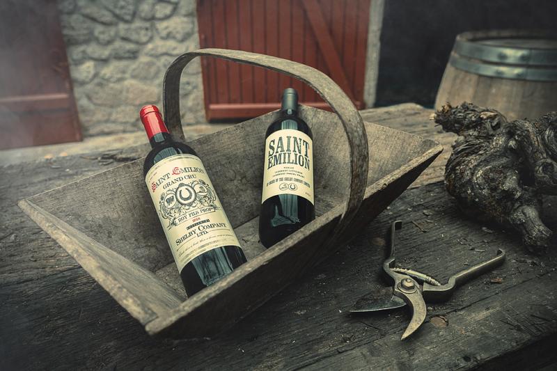 Two bottles of red wine Shelby Company and Saint-Emilion lying in a 1920s harvest basket