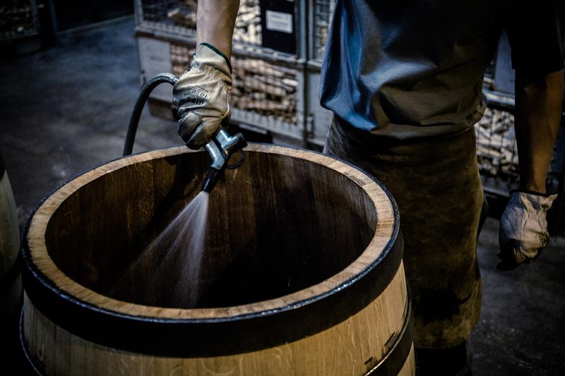 Barrel maker spraying water into the inside of a barrel being toasted